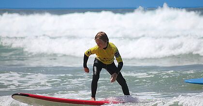 Surfendes Kind auf der Familienreise und Aktivreise im seaside surf camp in Frankreich. 
